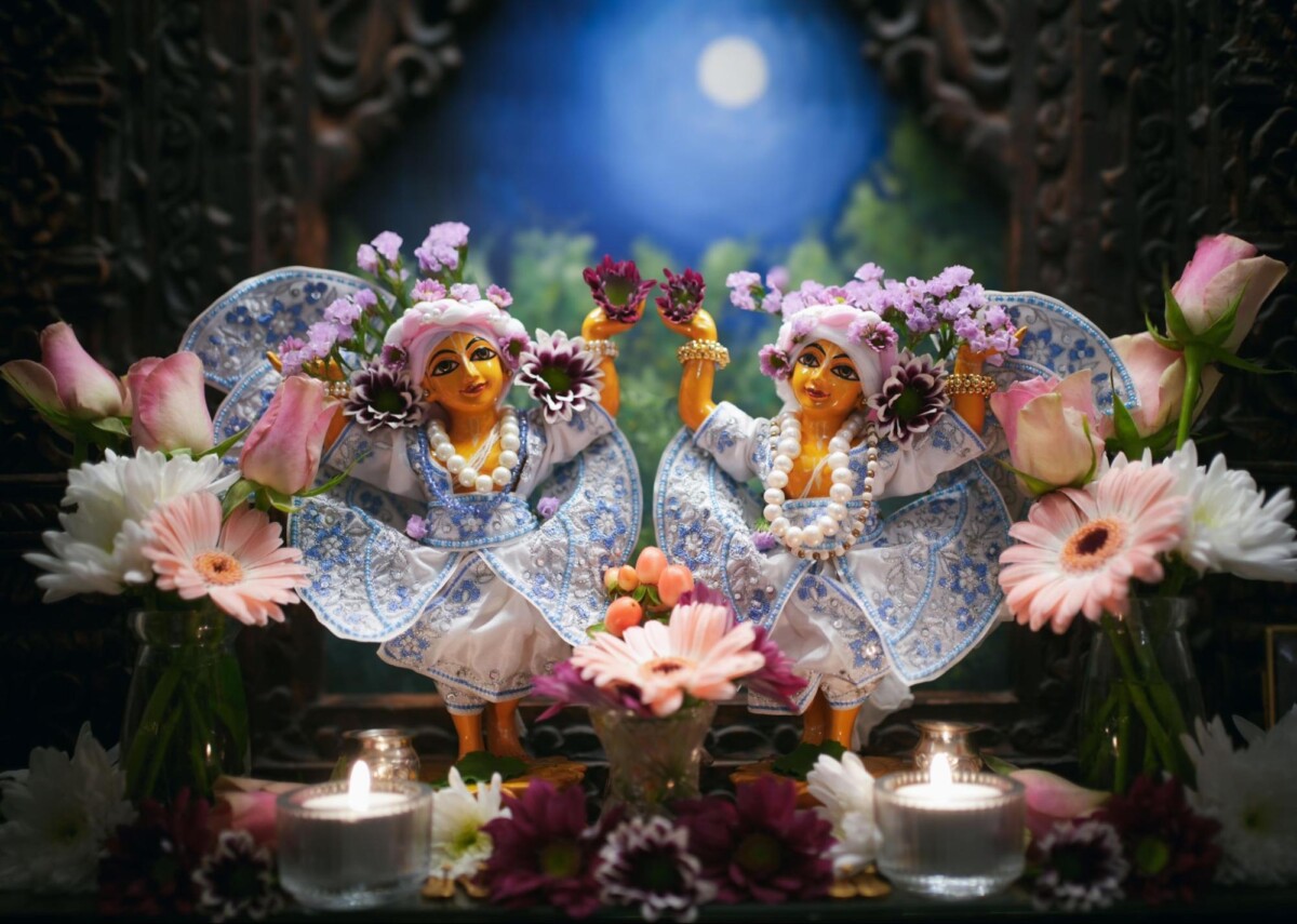 Icons of Chaitanya and Nityananda stand dressed and decorated in white and blue at a home mandir.