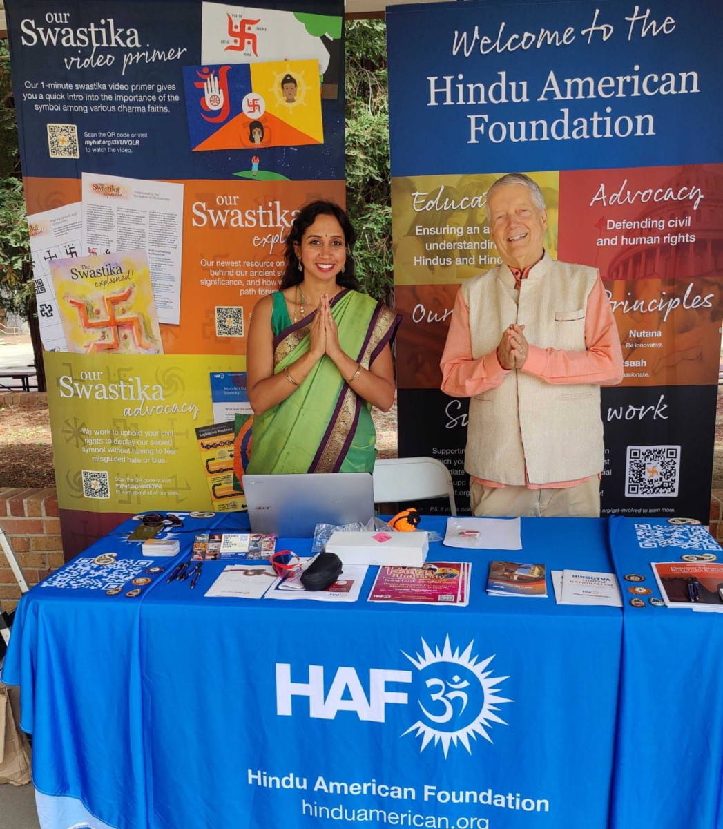 A Hindu woman and Hindu man pose behind a HAF booth at a local Sacramento festival.