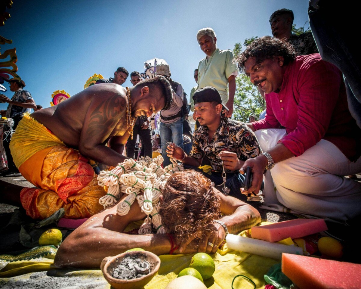 A woman lies on the ground as devotees prepare her to bear the kavadi.